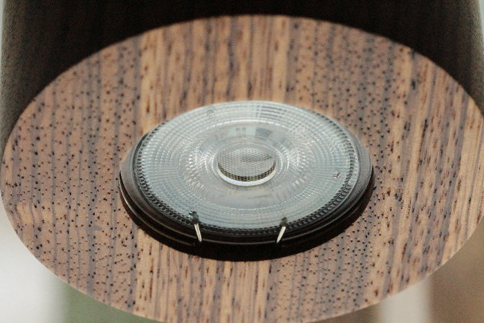 Round wood LED ceiling spotlight zebrano showing contrasting natural grain lines close-up view